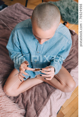 Woman preparing hand rolled cigarette with tobacco at the bed at home 76924998