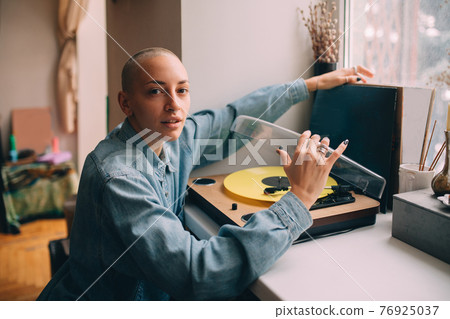 Woman sitting near her vinyl music player and preparing to listening music 76925037