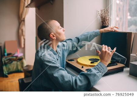 Woman sitting near her vinyl music player and preparing to listening music 76925049