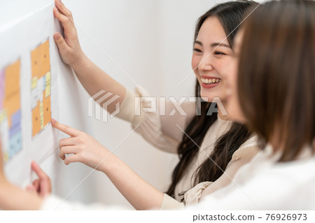 兩個女人一邊看房子的平面圖一邊開會的商業場景 兩個女人一邊看房子的平面圖一邊開會的商業場景 76926973