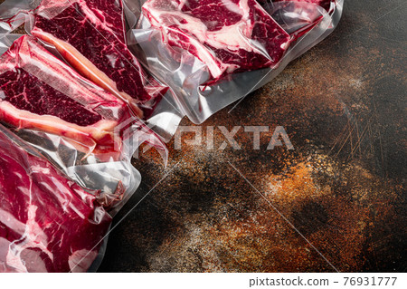 Beef steak vacuum sealed ready for sous vide cooking, tomahawk, t bone, club steak, rib eye and tenderloin cuts, on old dark rustic background, with copy space for text Beef steak vacuum sealed ready for sous vide cooking, tomahawk, t bone, club steak, rib eye and tenderloin cuts, on old dark rustic background, with copy space for text 76931777