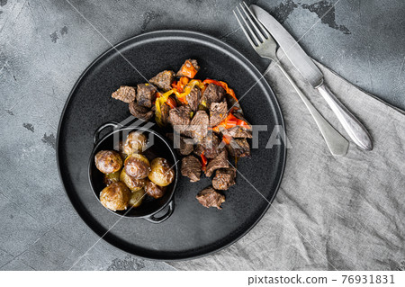 Beef meat stewed with potatoes, carrots and spices, on gray stone background, top view flat lay 76931831