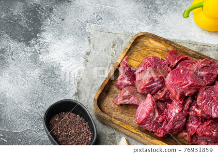 Raw ingredients for goulash. Fresh raw chopped beef with sweet bell pepper, on gray stone background, with copy space for text Raw ingredients for goulash. Fresh raw chopped beef with sweet bell pepper, on gray stone background, with copy space for text 76931859