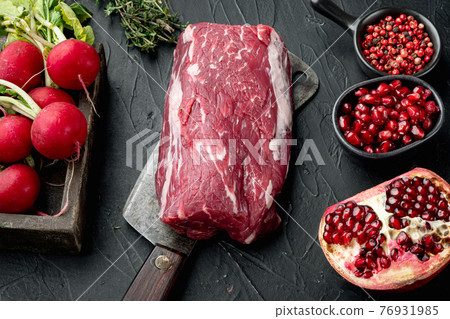 Fresh raw beef tenderloin with seasonings and rosemary, a whole uncut piece, on old butcher cleaver knife, on black stone background Fresh raw beef tenderloin with seasonings and rosemary, a whole uncut piece, on old butcher cleaver knife, on black stone background 76931985