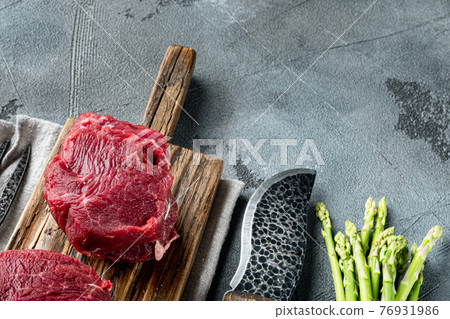 Beef fillet cut raw with ingredients, on gray stone background, with copy space for text 76931986
