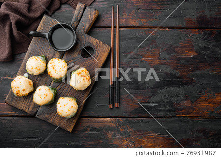 Baked sushi roll with shrimp and masago caviar cap. Traditional sushi restaurant dish, on old dark wooden table background, top view flat lay , with copyspace and space for text Baked sushi roll with shrimp and masago caviar cap. Traditional sushi restaurant dish, on old dark wooden table background, top view flat lay , with copyspace and space for text 76931987