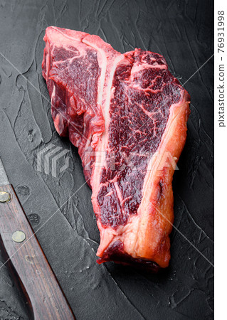 Classic fresh beef striploin steaks,T bone cut, on black stone background 76931998