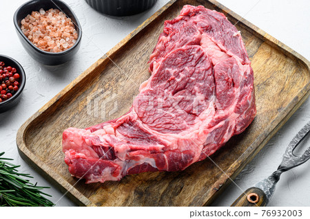Raw steak, pepper, herbs, garlic, rosemary from marbled organic beef meat, on white stone background 76932003