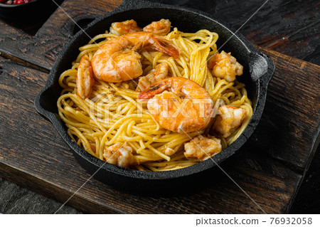 Traditional Italian dish. pasta with pesto ricotta parmesan and grilled seafood , in cast iron frying pan, on old dark wooden table Traditional Italian dish. pasta with pesto ricotta parmesan and grilled seafood , in cast iron frying pan, on old dark wooden table 76932058