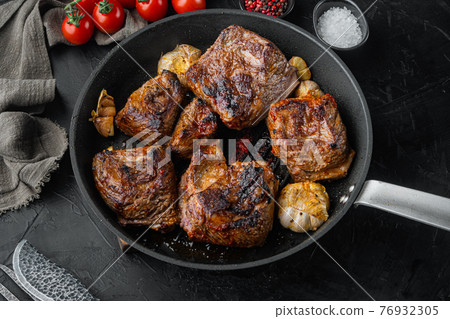 Baked short beef ribs , on black stone background Baked short beef ribs , on black stone background 76932305