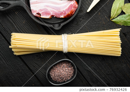 Wholemeal spaghetti ,Yellow long uncooked dried pasta, on black wooden background, top view flat lay 76932426