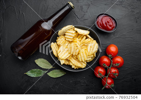 Potatoe chips, with bottle of beer , on black stone background, top view flat lay 76932504