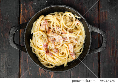 Pasta with egg sauce and ham, in cast iron frying pan, on old dark wooden table , top view flat lay Pasta with egg sauce and ham, in cast iron frying pan, on old dark wooden table , top view flat lay 76932520