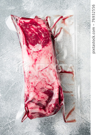 Rib eye marbled beef cut vacuum pack, on gray stone background, top view flat lay 76932556