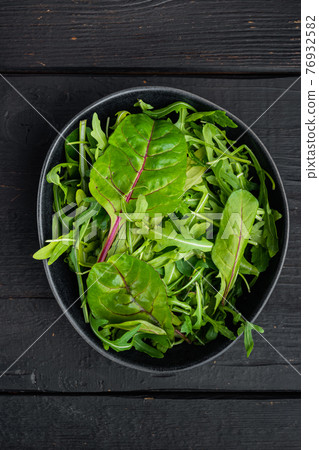 Healthy salad, leaves mix salad Arugula, Chard, on black wooden table background, top view flat lay Healthy salad, leaves mix salad Arugula, Chard, on black wooden table background, top view flat lay 76932582