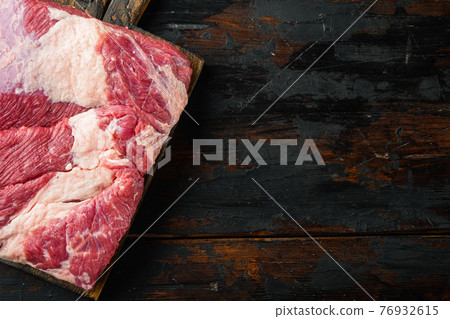 A whole piece of raw Beef Brisket, on old dark wooden table background, top view flat lay, with copy space for text 76932615
