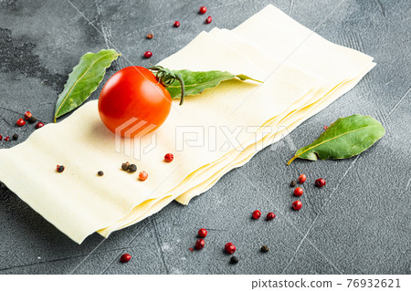 Lasagna dough sheets, with seasoning and herb, on gray stone background 76932621