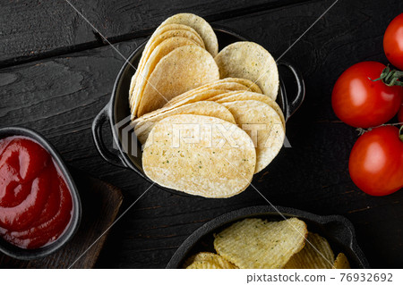 Crispy potato chips, on black wooden background Crispy potato chips, on black wooden background 76932692