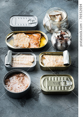 Salmon, tuna, trout mackerel and anchovy - Canned fish in tin cans, on gray background Salmon, tuna, trout mackerel and anchovy - Canned fish in tin cans, on gray background 76932694