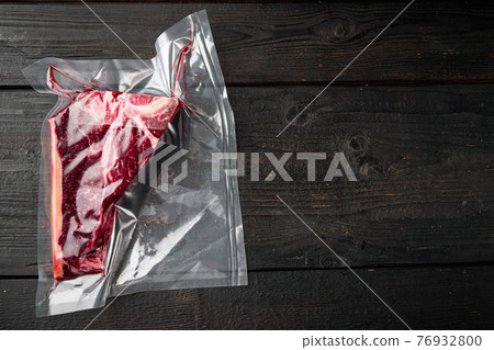 T-bone or florentine dry aged raw marbled beef steak in vacuum packaging, on black wooden background, top view flat lay, with copy space for text T-bone or florentine dry aged raw marbled beef steak in vacuum packaging, on black wooden background, top view flat lay, with copy space for text 76932800