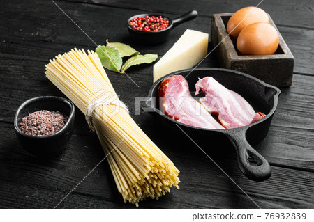 Traidtional Italian Pasta Carbonara Ingredients. Bacon, Spaghetti, Parmesan and pecorino cheese, egg, garlic, on black wooden background Traidtional Italian Pasta Carbonara Ingredients. Bacon, Spaghetti, Parmesan and pecorino cheese, egg, garlic, on black wooden background 76932839