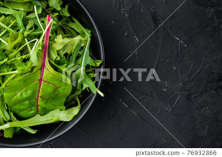 Herb green salad with arugula and Mangold, Swiss chard, on black stone background, top view flat lay, with copy space for text Herb green salad with arugula and Mangold, Swiss chard, on black stone background, top view flat lay, with copy space for text 76932866