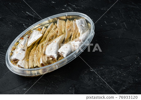 Canned Anchovies, in plastic container, on black background, with copyspace and space for text 76933120