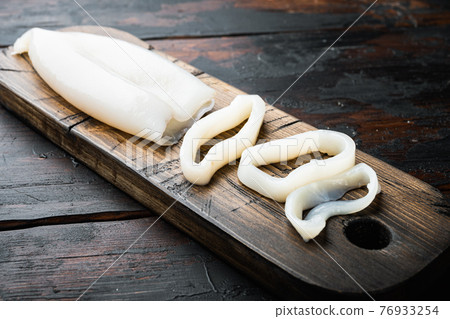 Seafood cuttlefish on cutting board over dark rustic wooden background Seafood cuttlefish on cutting board over dark rustic wooden background 76933254