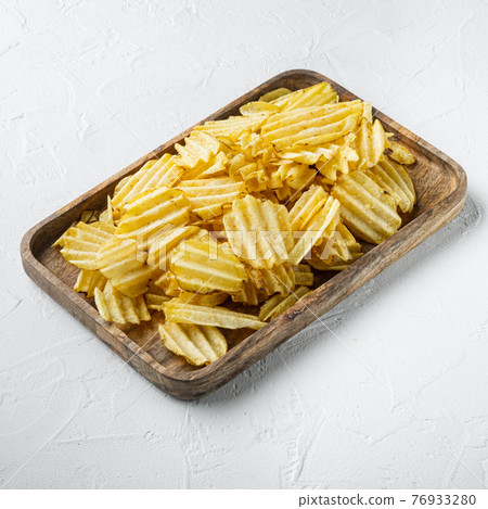 Delicious crispy potato chips, on white stone surface 76933280