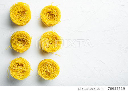 Durum wheat semolina homemade egg pasta tagliarini, on white stone surface, top view flat lay, with copy space for text Durum wheat semolina homemade egg pasta tagliarini, on white stone surface, top view flat lay, with copy space for text 76933519