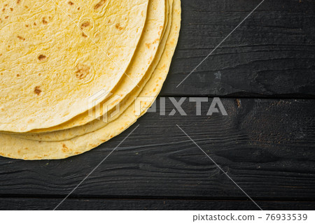 Fresh yellow corn tortillas, on black wooden table background, top view flat lay with copy space for text 76933539