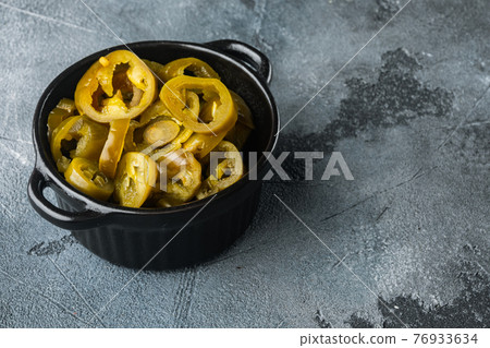 Pickled or canned Jalapeno peppers, on gray background with copy space for text Pickled or canned Jalapeno peppers, on gray background with copy space for text 76933634