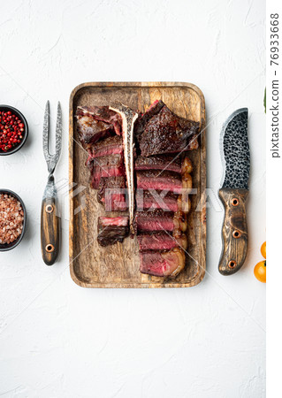 Fresh juicy medium rare Sliced and roast T bone or porterhouse beef meat Steak, on white stone background, top view flat lay, with copy space for text 76933668