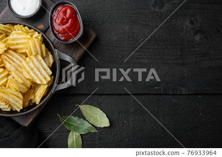 Salty potato chips snack , on black wooden background, top view flat lay, with copy space for text 76933964