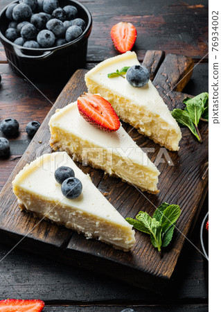 New York cheesecake or classic cheesecake with fresh berries, on old dark wooden table background New York cheesecake or classic cheesecake with fresh berries, on old dark wooden table background 76934002