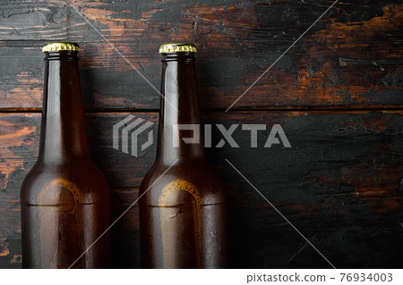 Fresh beer in glass bottles, on old dark wooden table , top view flat lay, with copy space for text 76934003