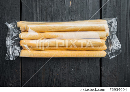 Breadsticks with olive oil, on black wooden background, flat lay Breadsticks with olive oil, on black wooden background, flat lay 76934004