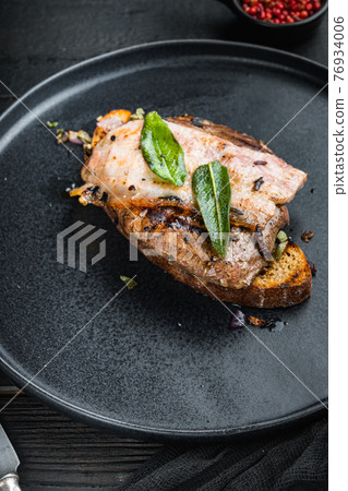 Liver bacon and onions on bread cooked meal on plate on black surface Liver bacon and onions on bread cooked meal on plate on black surface 76934006