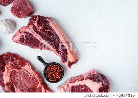 Various cuts of marbled beef meat and dry aged steaks, tomahawk, t bone, club steak, rib eye and tenderloin cuts, on white stone background, top view flat lay, with copy space for text Various cuts of marbled beef meat and dry aged steaks, tomahawk, t bone, club steak, rib eye and tenderloin cuts, on white stone background, top view flat lay, with copy space for text 76934019