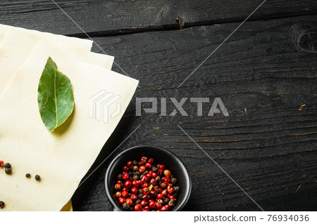 Organic lasagna pasta sheets, with seasoning and herb, on black wooden table background, with copy space for text Organic lasagna pasta sheets, with seasoning and herb, on black wooden table background, with copy space for text 76934036
