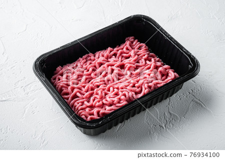 Fresh minced meat in plastic box packaging tray, on white stone background Fresh minced meat in plastic box packaging tray, on white stone background 76934100
