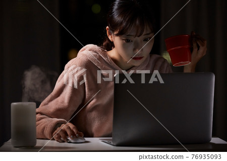 Young woman working from home at midnight 76935093