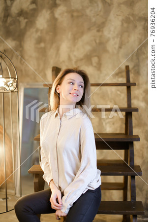 Portrait of young blonde girl sitting on wooden stairs. Portrait of young blonde girl sitting on wooden stairs. 76936204