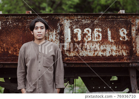 Portrait of smiling handsome Asian man standing at public train station. Young Man Standing in Old Vintage Train 76936710