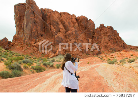 Female tourist taking photos in mountains Female tourist taking photos in mountains 76937297