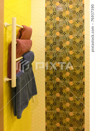 Empty bathroom with gray colored shower wall behind white metal warming rack 76937390