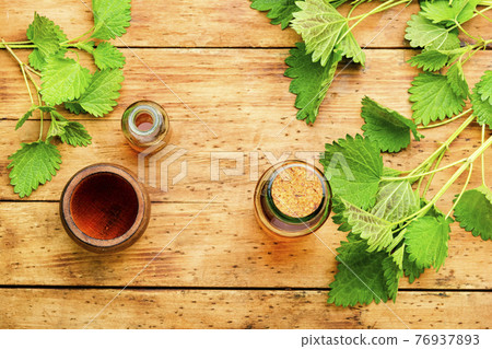Glass bottle of nettle tincture on wooden table 76937893