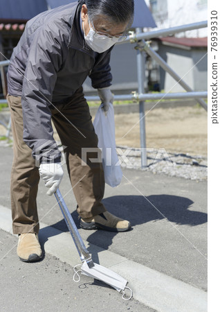 Senior man picking up a littering mask Senior man picking up a littering mask 76939310