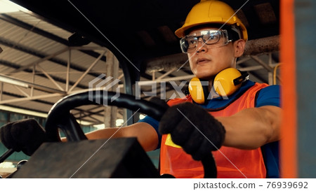Skillful worker drives forklift in the factory . 76939692