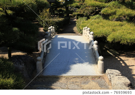 The stone bridge in the park is covered with a shadow of a tree The stone bridge in the park is covered with a shadow of a tree 76939693